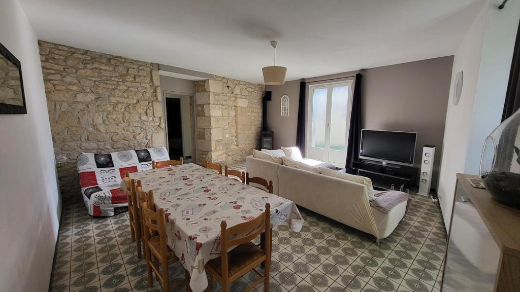 a living room with a table and a stone wall at Ma Location Saisonnière in Chasseneuil-du-Poitou