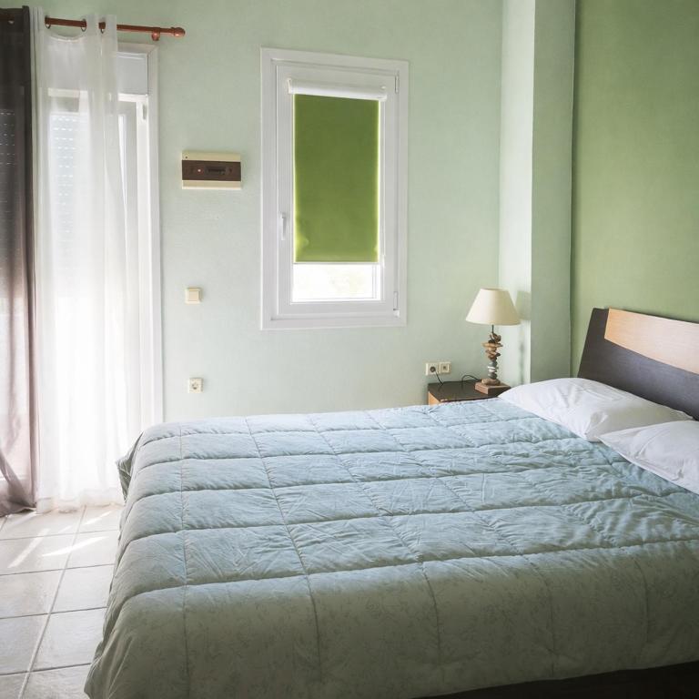 a bedroom with a large bed and a window at Zannikos Rooms in Ermoupoli