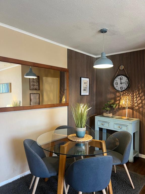 a dining room with a table and chairs and a clock at Cómodo departamento en Curicó in Curicó