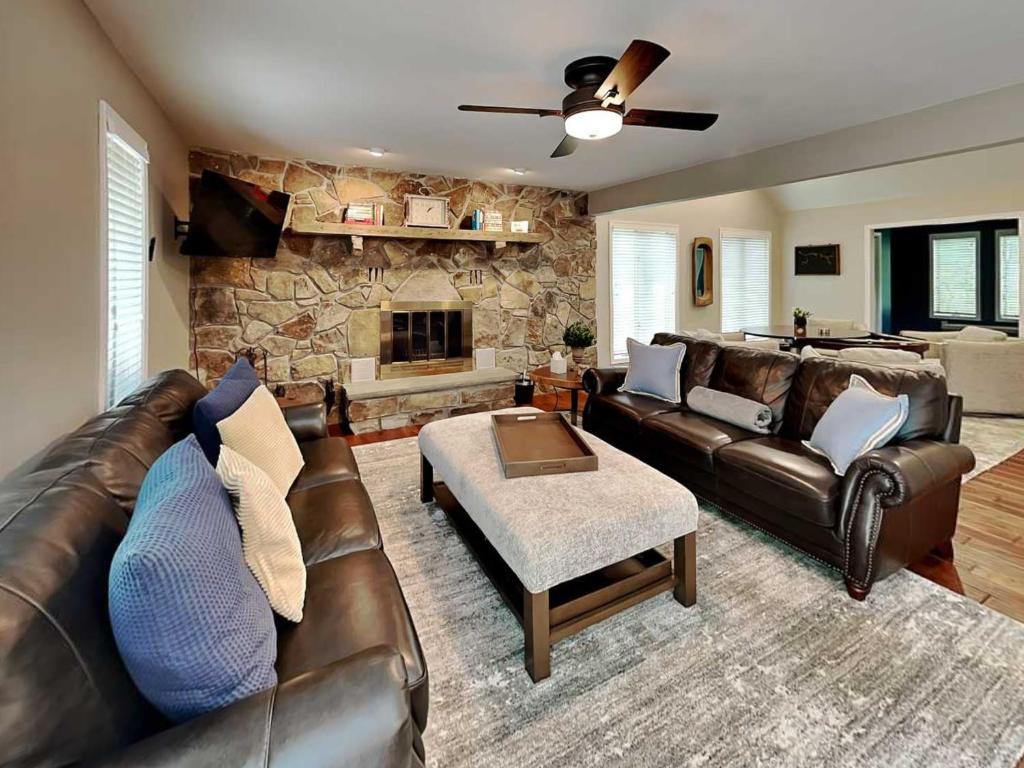 a living room with a leather couch and a stone fireplace at Yes Deer in Oakland