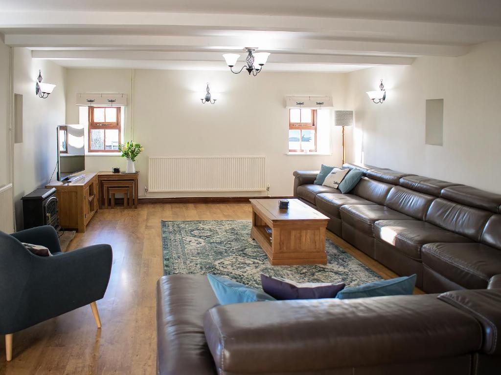 a living room with a leather couch and a table at Whitehouse Farm in Hartington
