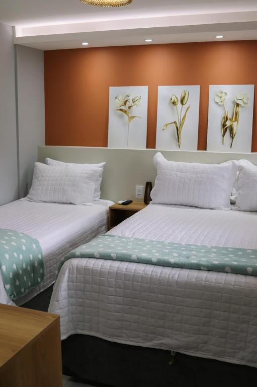 two beds in a room with paintings on the wall at Casinha de Aldeia in Aldeia Velha