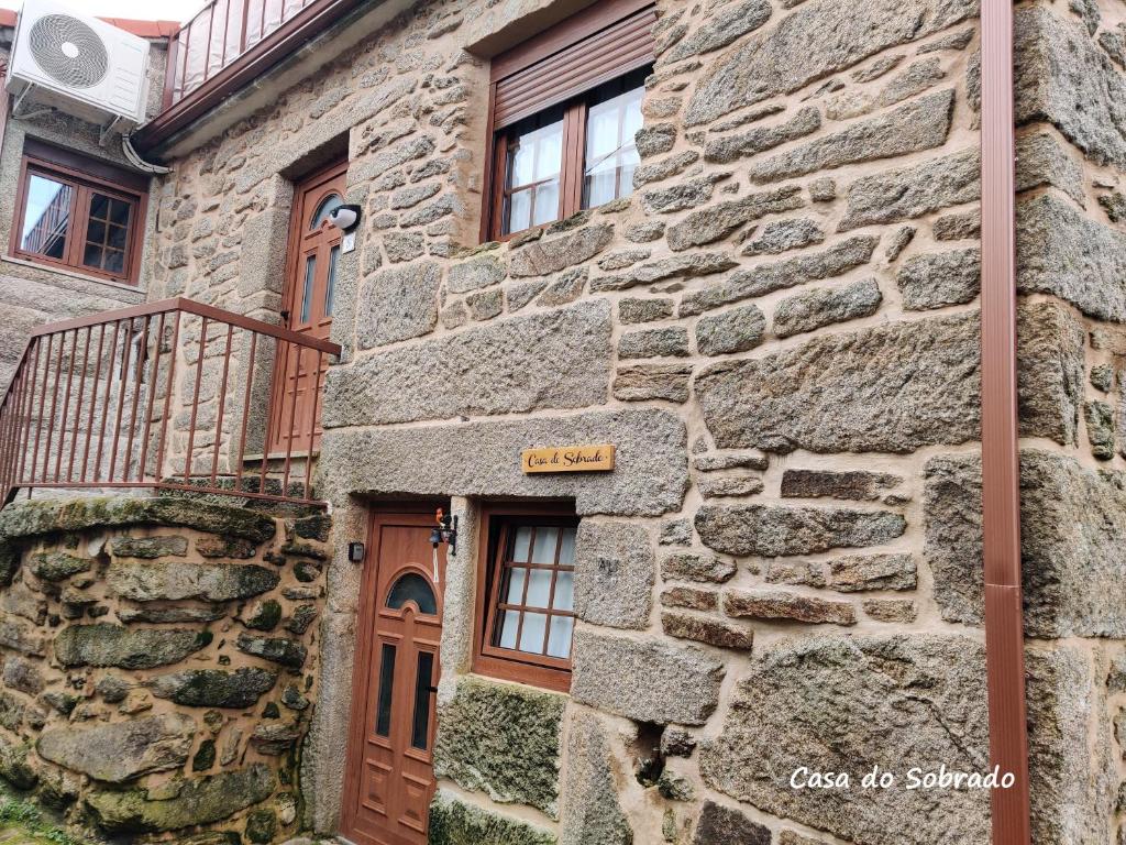 a stone building with a wooden door and windows at Casa do Sobrado-Gralhas-Montalegre in Gralhas