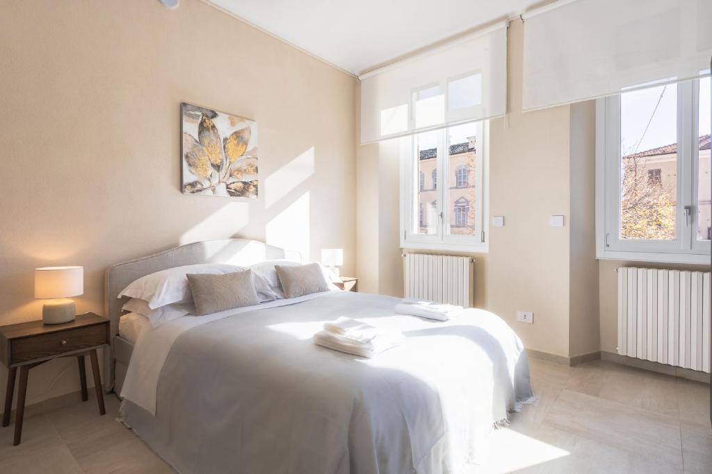 a bedroom with a white bed and two windows at Casa Scioli in Caraglio