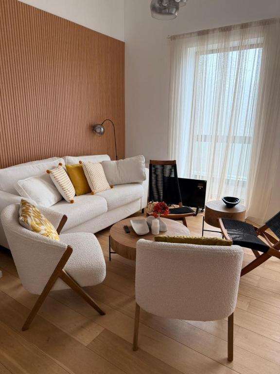 a living room with a white couch and chairs at White & Wood Suite C302, at Euphoria SPA Borovets in Borovets