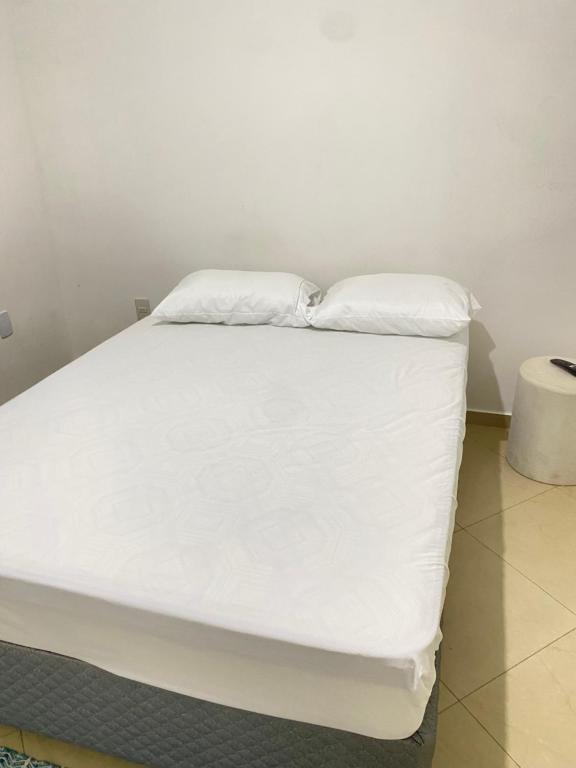 a white bed with two pillows on top of it at Casa de hóspedes âncora Lu in São Pedro da Aldeia