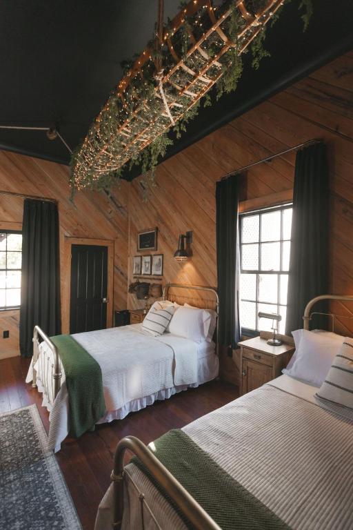 two beds in a room with wooden walls and windows at The Gilded Lady - The Cypress Suite in Pensacola