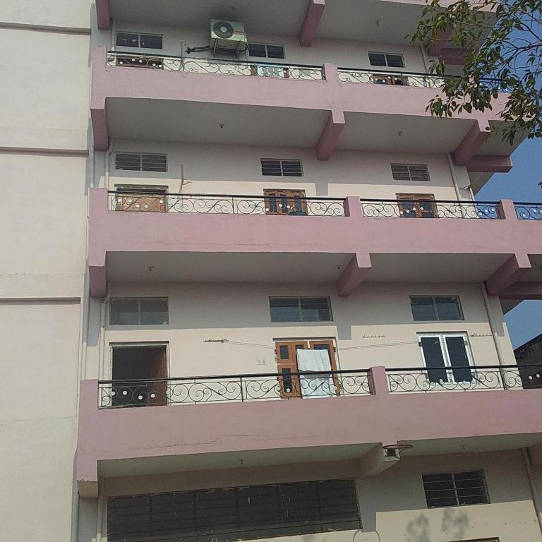 a tall pink building with balconies on it at Ladies homestay in Jhunjhunūn