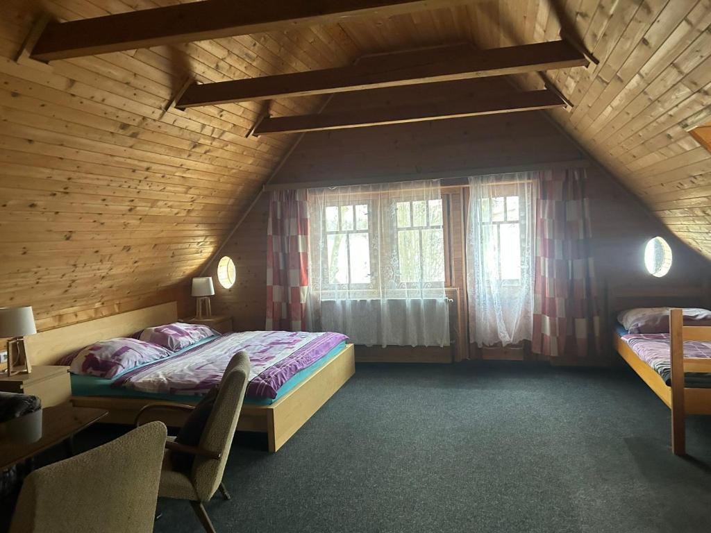 a attic bedroom with two beds and a window at Hostinec Na hrázi in Hamr na Jezeře