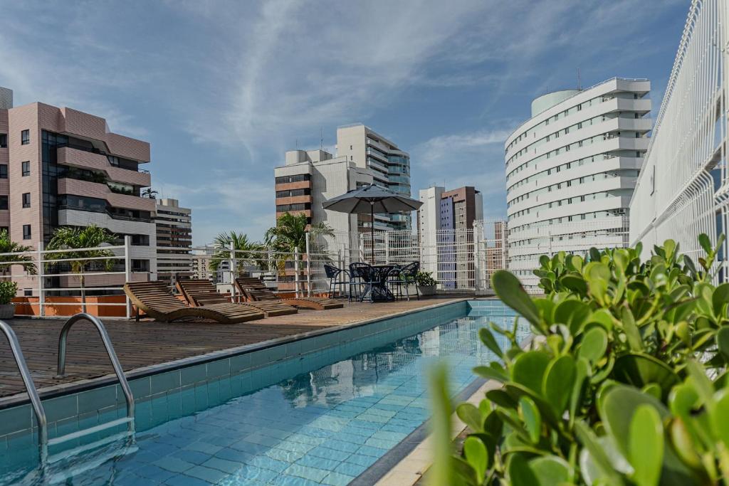 a swimming pool with chairs and an umbrella in a city at D8 Hotel in Fortaleza