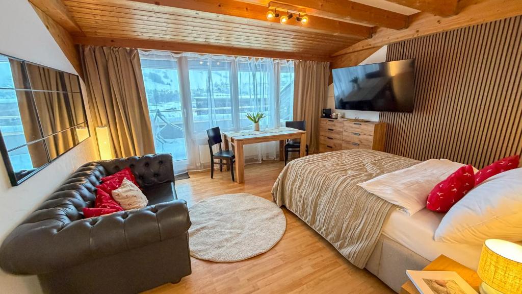 a bedroom with a bed and a desk and a television at PlanB Stay in Samedan