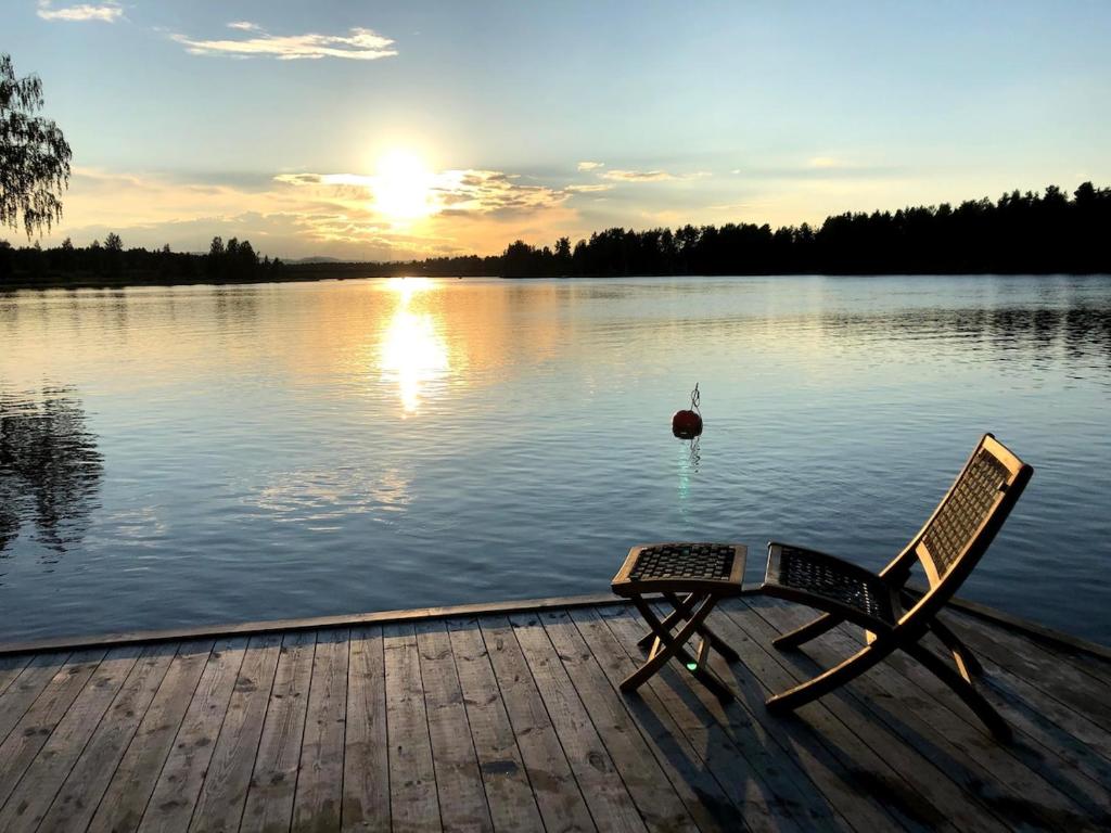 a chair sitting on a dock next to a lake at Lägenhet centralt i Mora in Mora