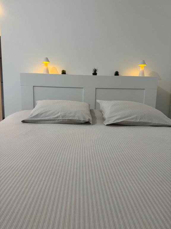 a white bed with two pillows in a bedroom at Studio, sea side in Berck-sur-Mer