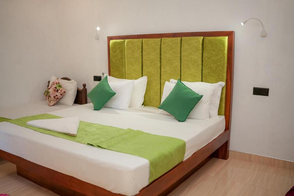 a bedroom with a large bed with green and white pillows at Gimanhala Thisawewa in Anuradhapura