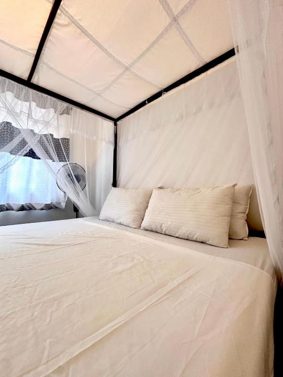 a bed in a tent with white sheets and pillows at The horezt in Kamburugamuwa
