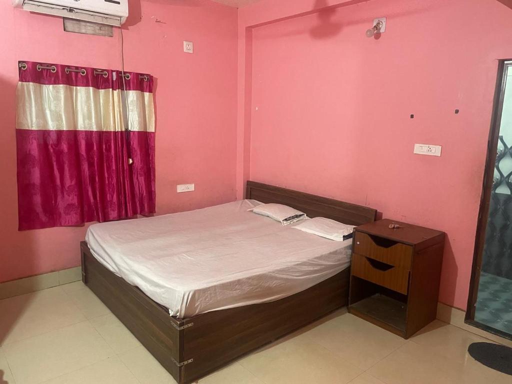 a small bed in a room with pink walls at Care Guest House in Bhubaneshwar
