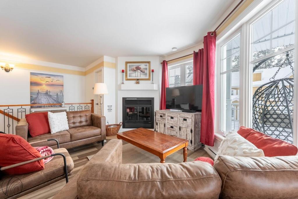 a living room with couches and a tv at Condo Lac Archambault Fireplace beach in Saint-Donat-de-Montcalm