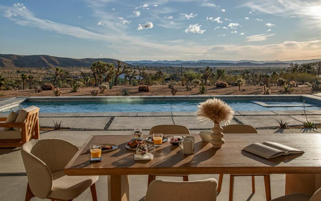a dining table and chairs with a view of a pool at Pool - Spa - Fire pit - Views - BBQ - Bella Nova in Joshua Tree