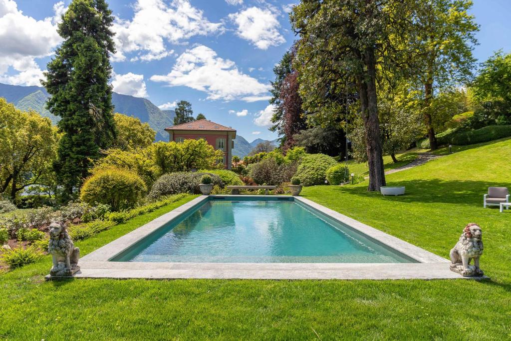 two dogs sitting next to a swimming pool in a yard at Villa Artemisia by MyVillaCollection in Lenno