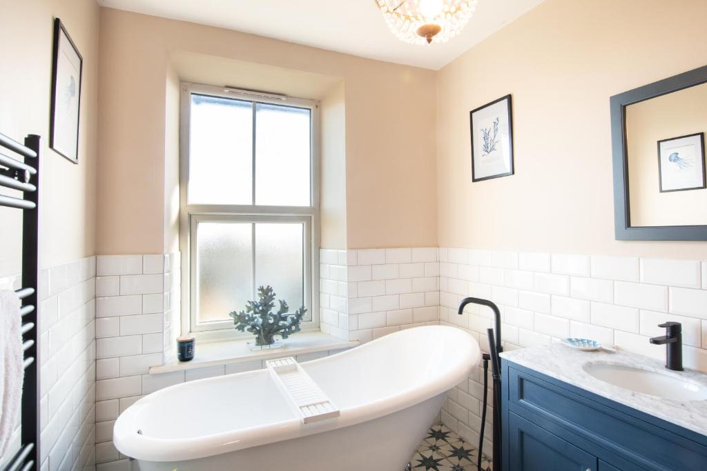 a bathroom with a tub and a sink at Northern Hideaways, Darling Cottage in Seahouses