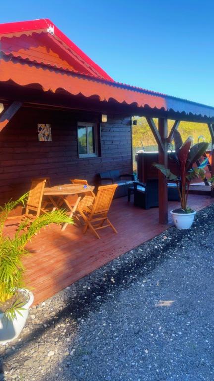 a house with a wooden deck with chairs and a table at Villa Eden hibiscus in Petit-Canal