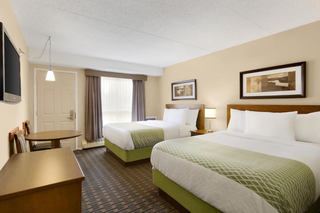 a hotel room with two beds and a flat screen tv at Colonial Square Inn & Suites in Saskatoon