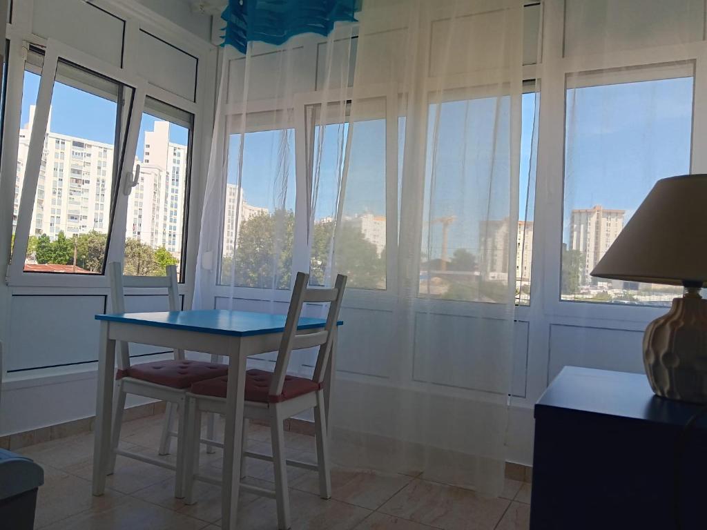 a table and chairs in a room with windows at Casa do Luiz in Lisbon