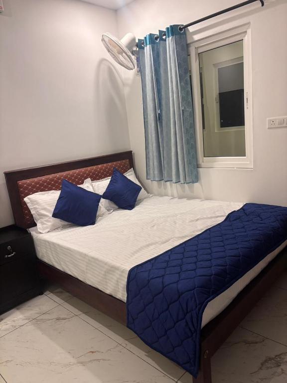 a bedroom with a bed with blue sheets and a window at Mount Elbrus Home stay in Devikolam
