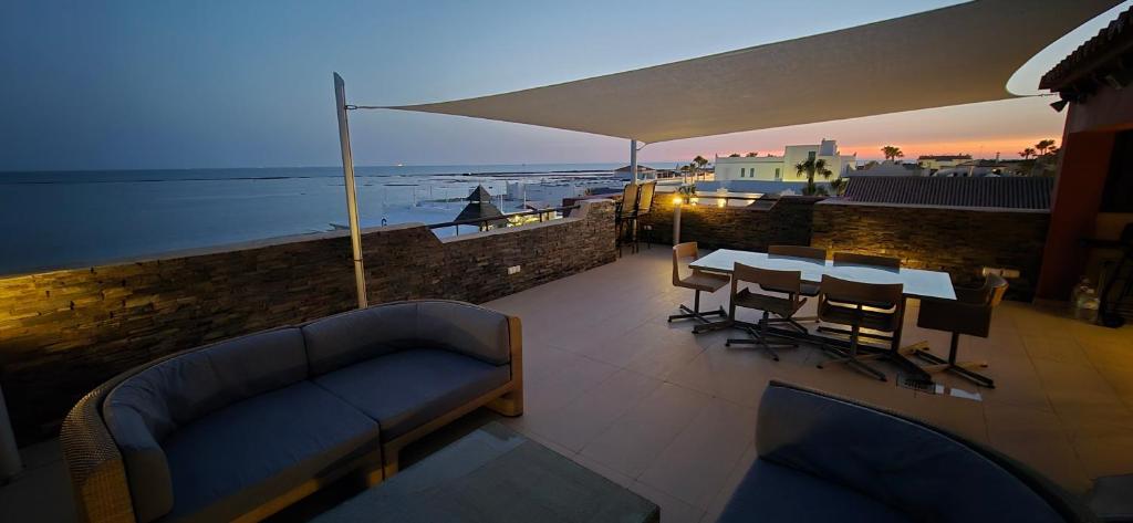 a patio with a couch and a table and chairs at Espectacular ático en 1°linea playa in Rota