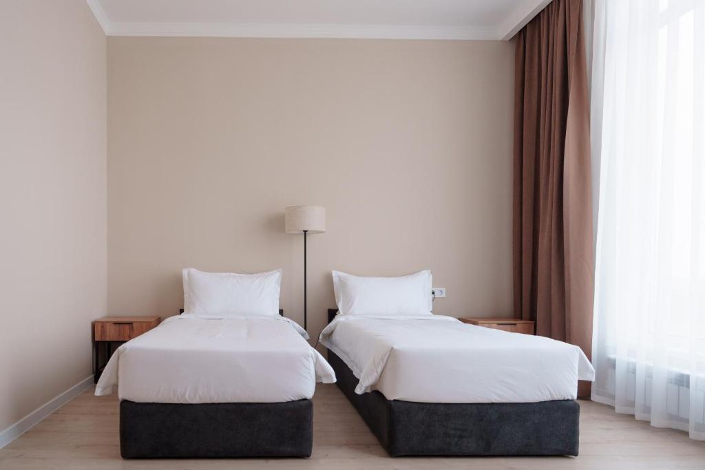 a bedroom with two beds with white sheets and a window at Ton Azure Hotel in Tong