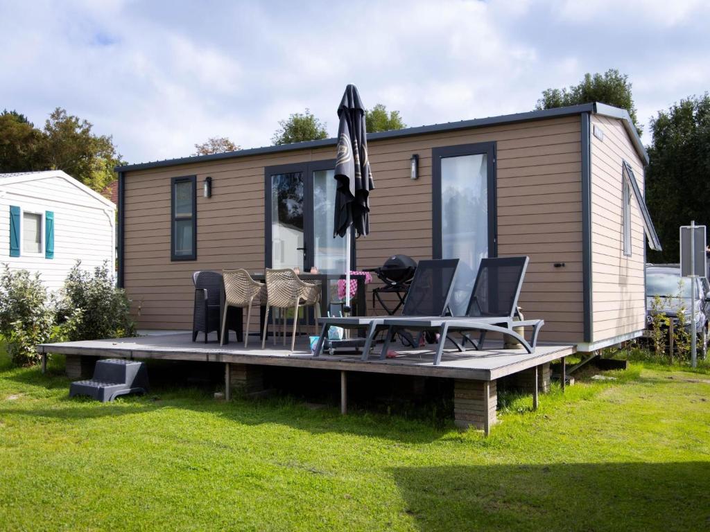 a tiny house with a deck with chairs and an umbrella at Wadden lodge comfort in Westerland