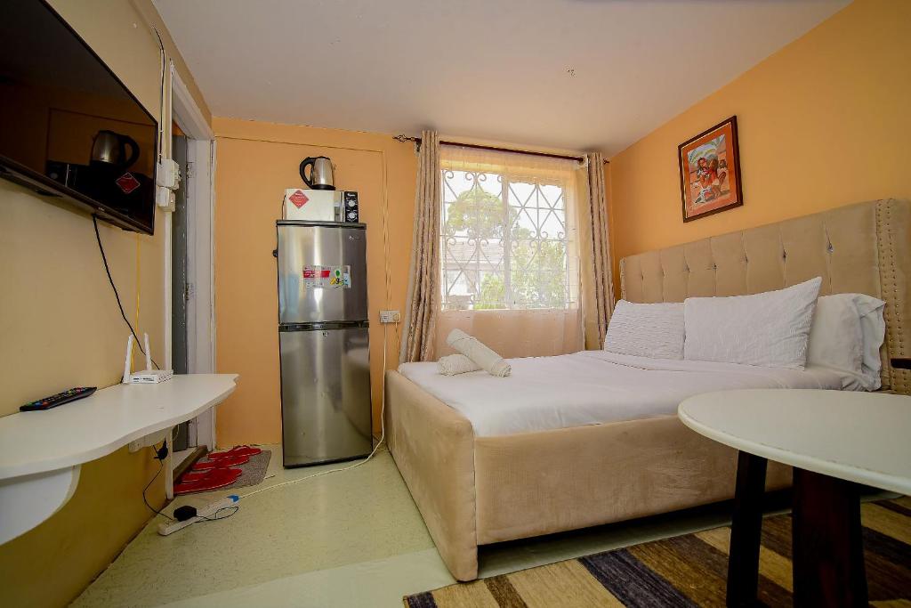 a small bedroom with a bed and a refrigerator at Maurine Homestays in Eldoret