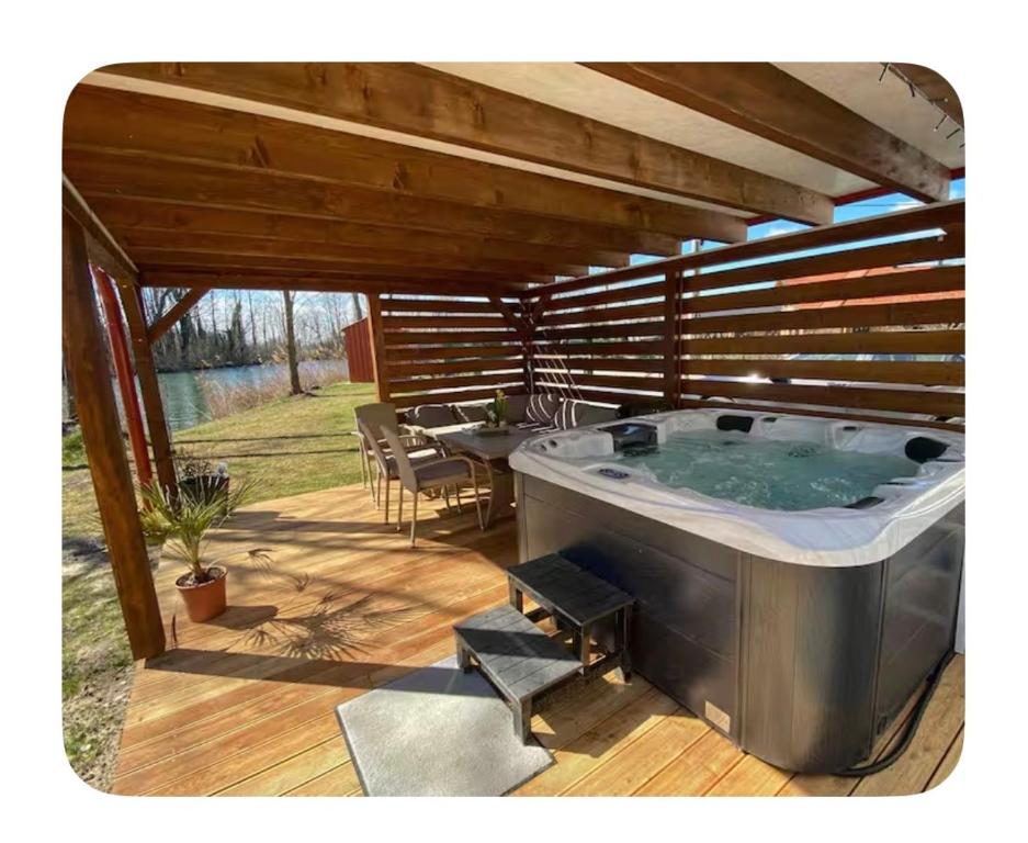 a hot tub on a deck with a table and chairs at Riverside Home Szigetköz in Dunasziget