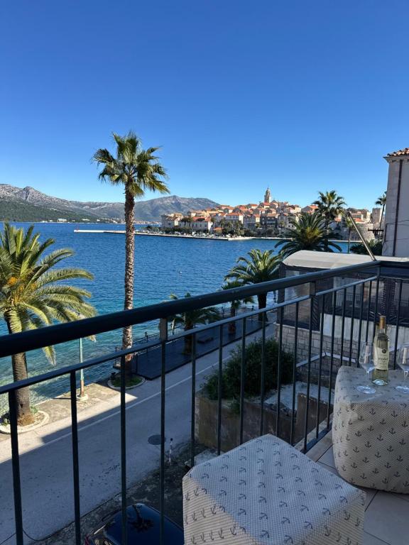 a balcony with a view of the water and a palm tree at The Korčula Outlook - Bedrooms in Korčula