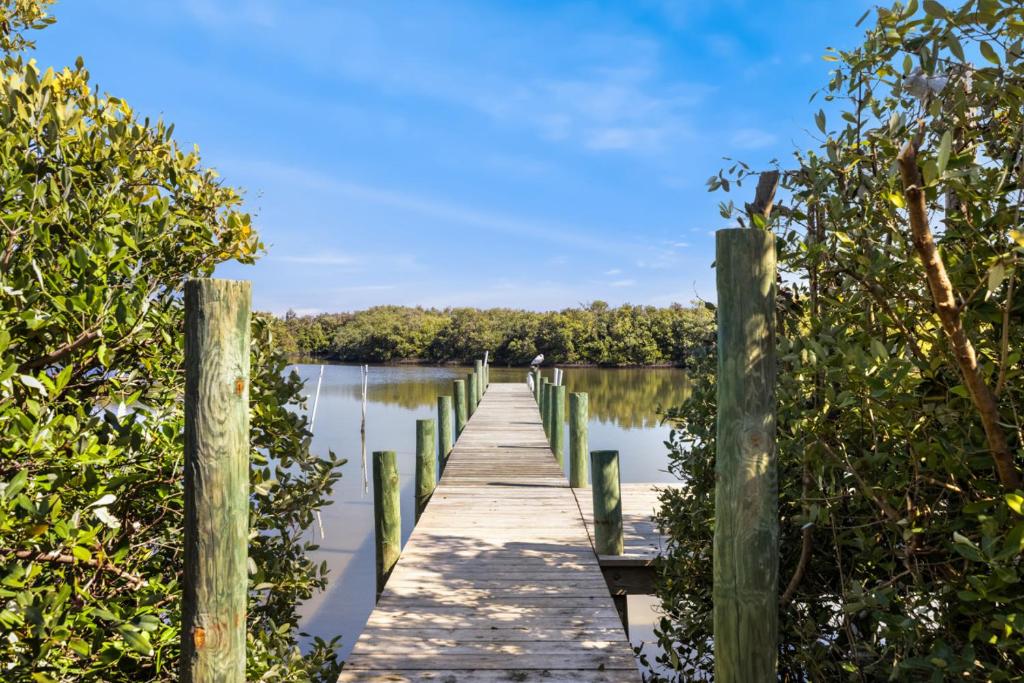 a wooden dock on a lake with trees at A Cedar Key Dock Holiday! in Cedar Key