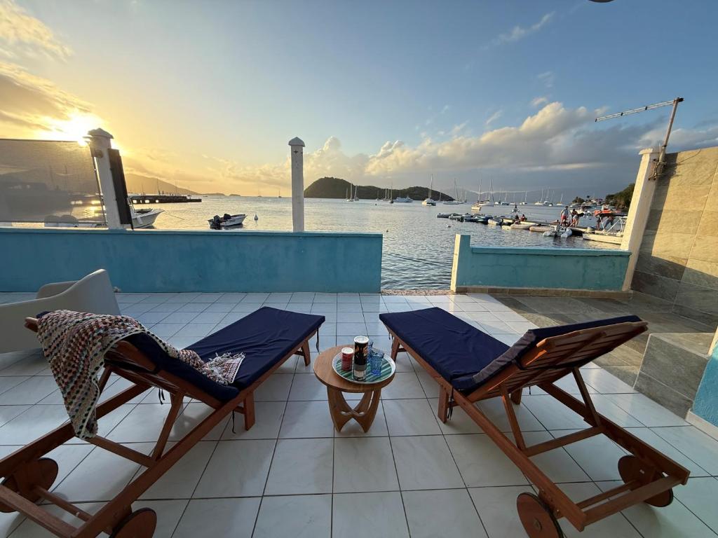 two chairs and a table on a patio with the water at KazParadis les Saintes in Terre-de-Haut