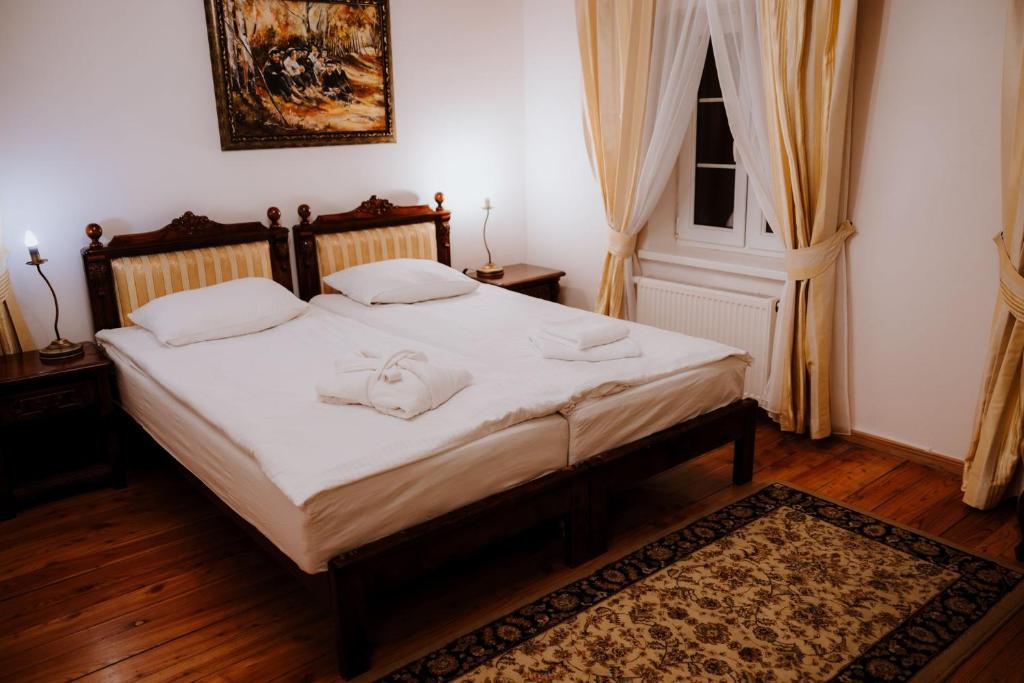 Twin beds with carved wooden headboards, white linens, decorative rug, soft bedside lighting.