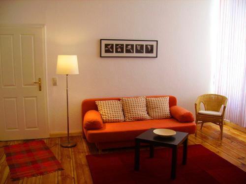 uma sala de estar com um sofá laranja e uma mesa em Apartment Schulz em Berlim