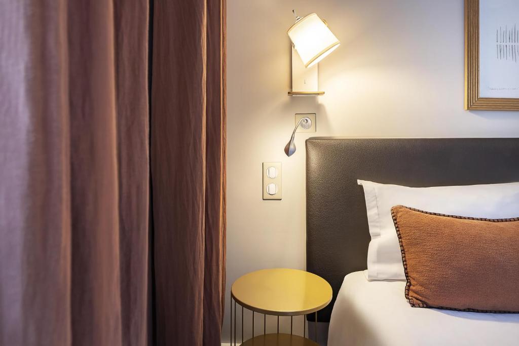 ein Schlafzimmer mit einem Bett, einem Tisch und einer Lampe in der Unterkunft Best Western Aramis Saint Germain in Paris