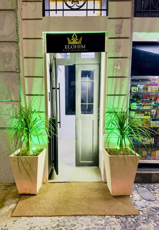 an open door of a store with two potted plants at Elohim Residencial in Rio de Janeiro