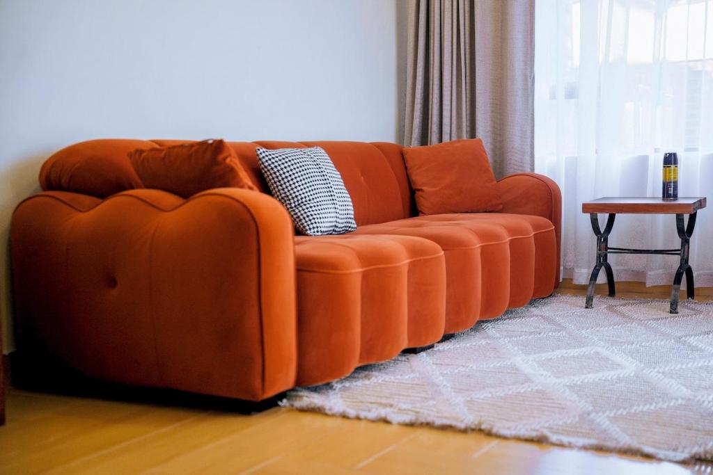 an orange couch in a living room with a table at Sunderdale in Gweru