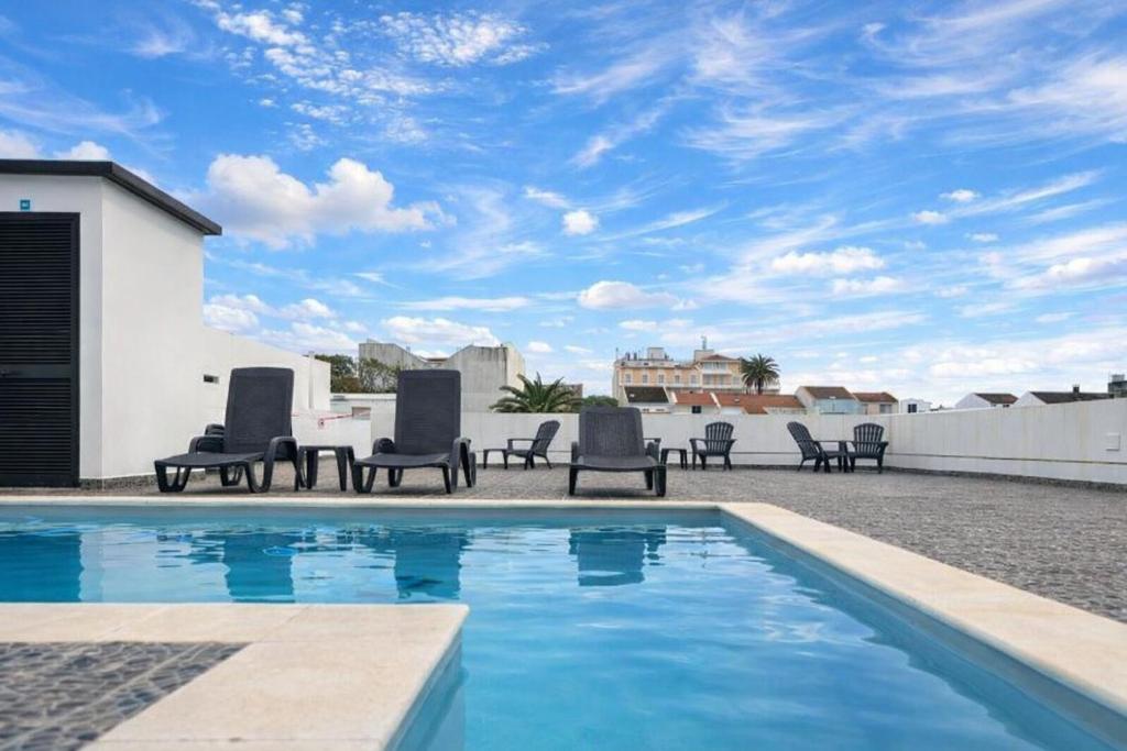 a pool with chairs and a table on a rooftop at The Rock Hostel in Ponta Delgada