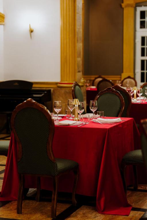 Intimate restaurant table with red tablecloth, wine glasses and green upholstered chairs.