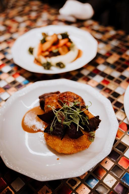 Crispy golden cake topped with mushrooms and microgreens on white plate, mosaic table.