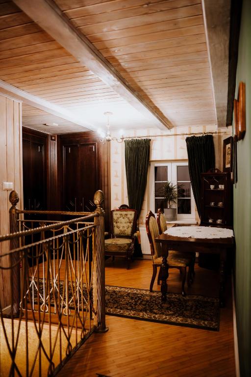 Cozy upstairs landing with vintage dining set, upholstered chair, ornate metal railing, warm lighting.