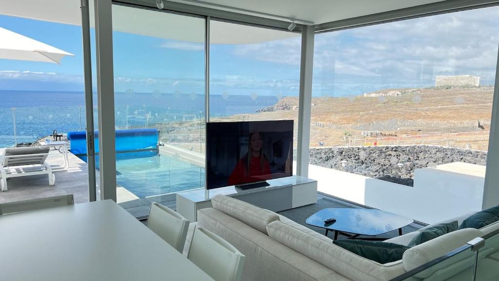 a living room with a tv and a large window at Luxurious villa with ocean views in Callao Salvaje