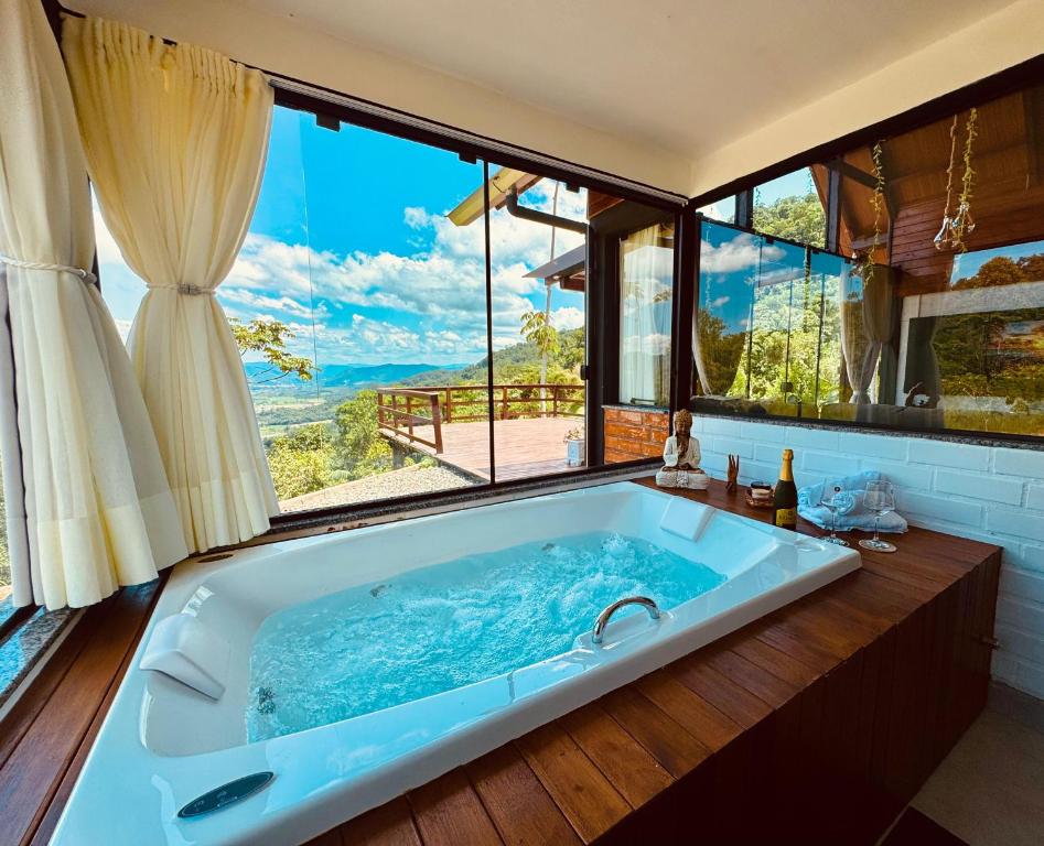 a large bath tub in a bathroom with a large window at Chalé Mirante dos Anjos in Rodeio