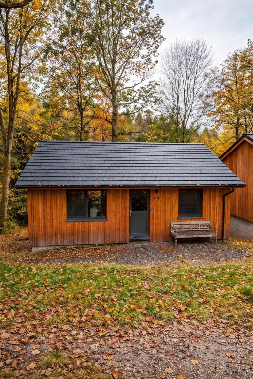 a wooden building with a bench in front of it at Au Bois Chantant in Somme-Leuze