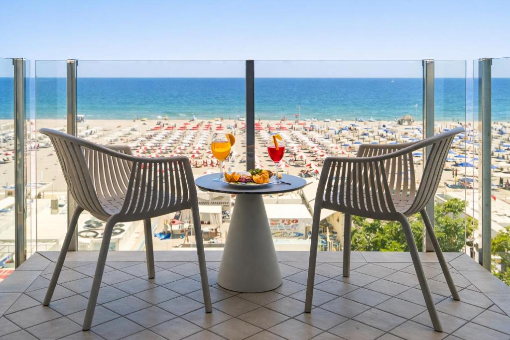 a table with two chairs and a view of the beach at Hotel Regina Fronte Mare in Rimini