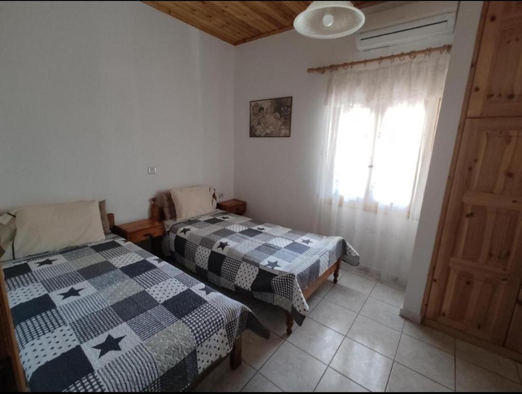 two beds in a room with a window at Sunny Home in Anaxos